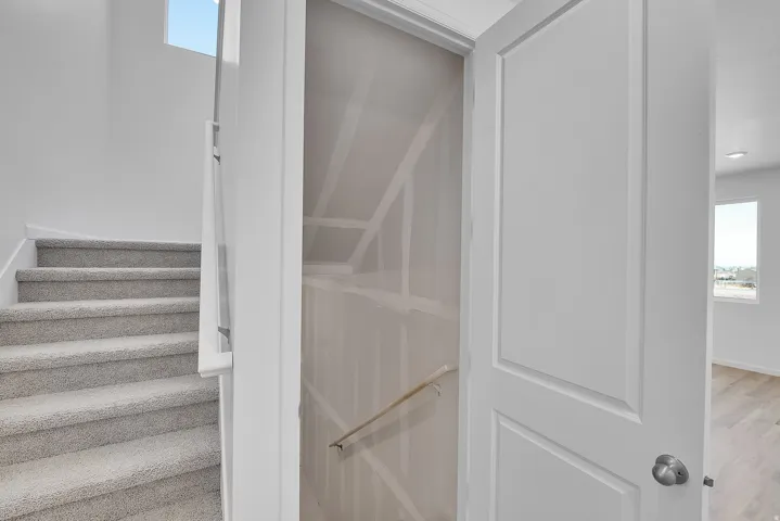 Carpeted staircase with white risers and a contemporary metal handrail