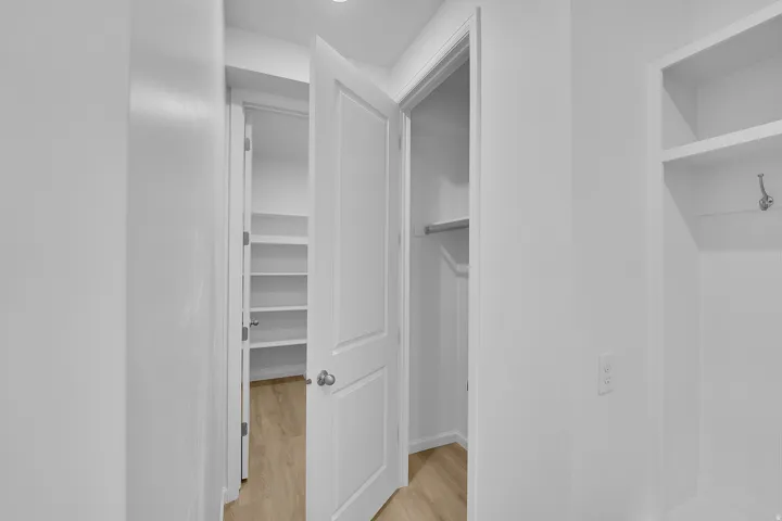 Built-in shelving, closet with hanging rod, wood-finish flooring, recessed lighting, and wall-mounted electrical outlets