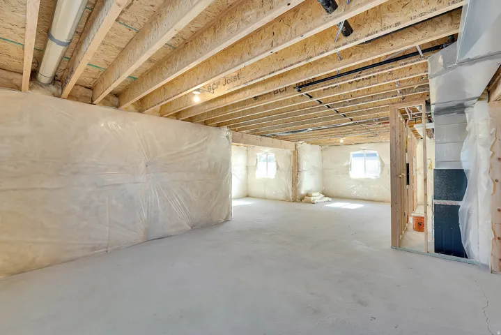 Unfinished basement with concrete flooring, exposed ceiling joists, and framed partition walls