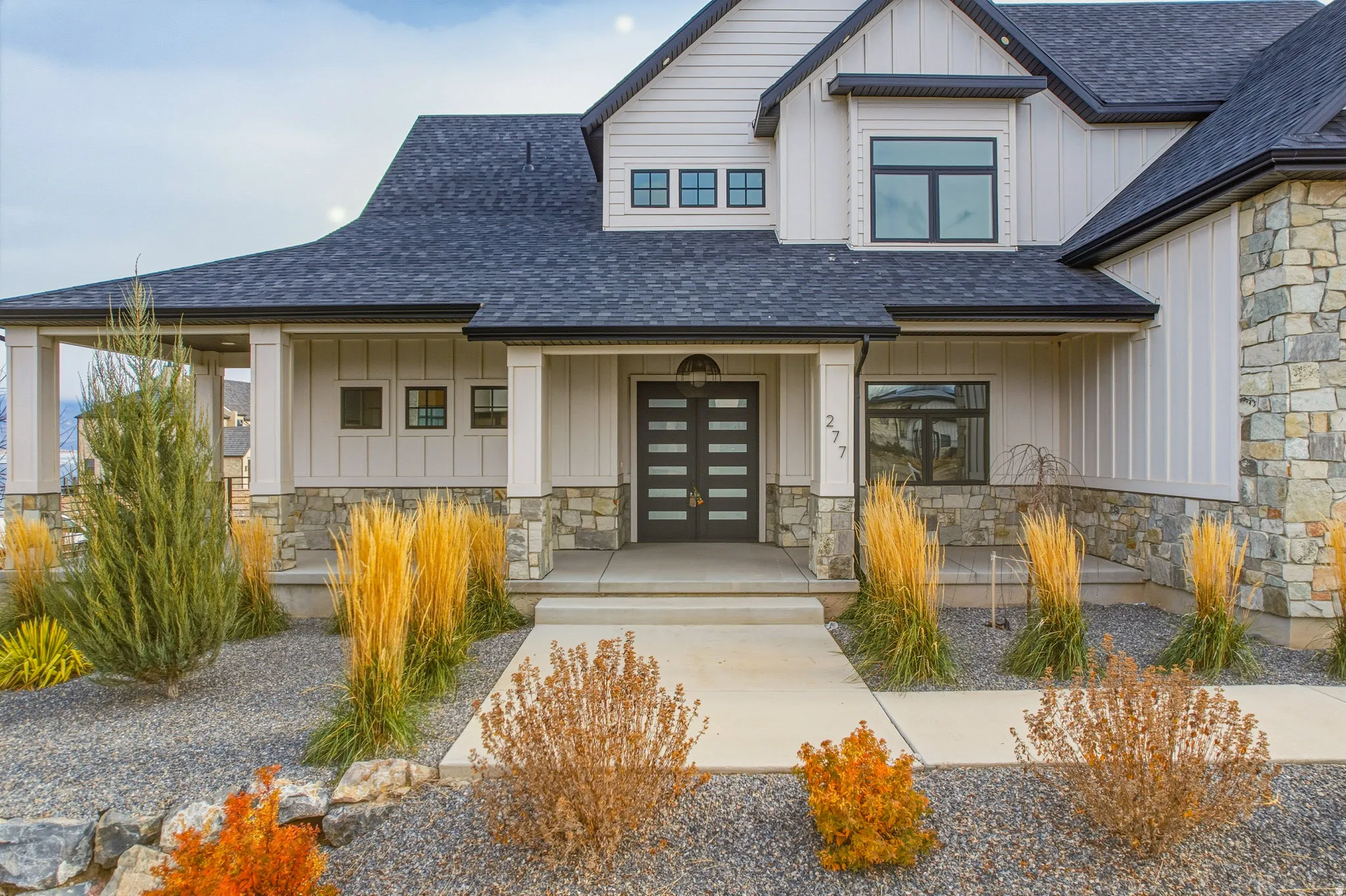 Contemporary exterior featuring a dark composite shingle roof, light-colored siding, and stone accents