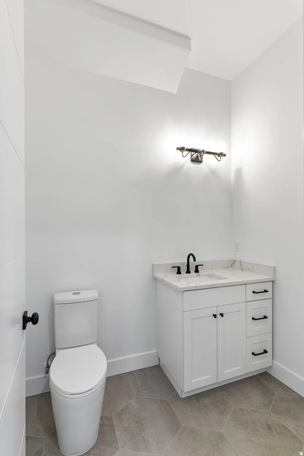White vanity with black hardware, stone-finish countertop, and black faucet