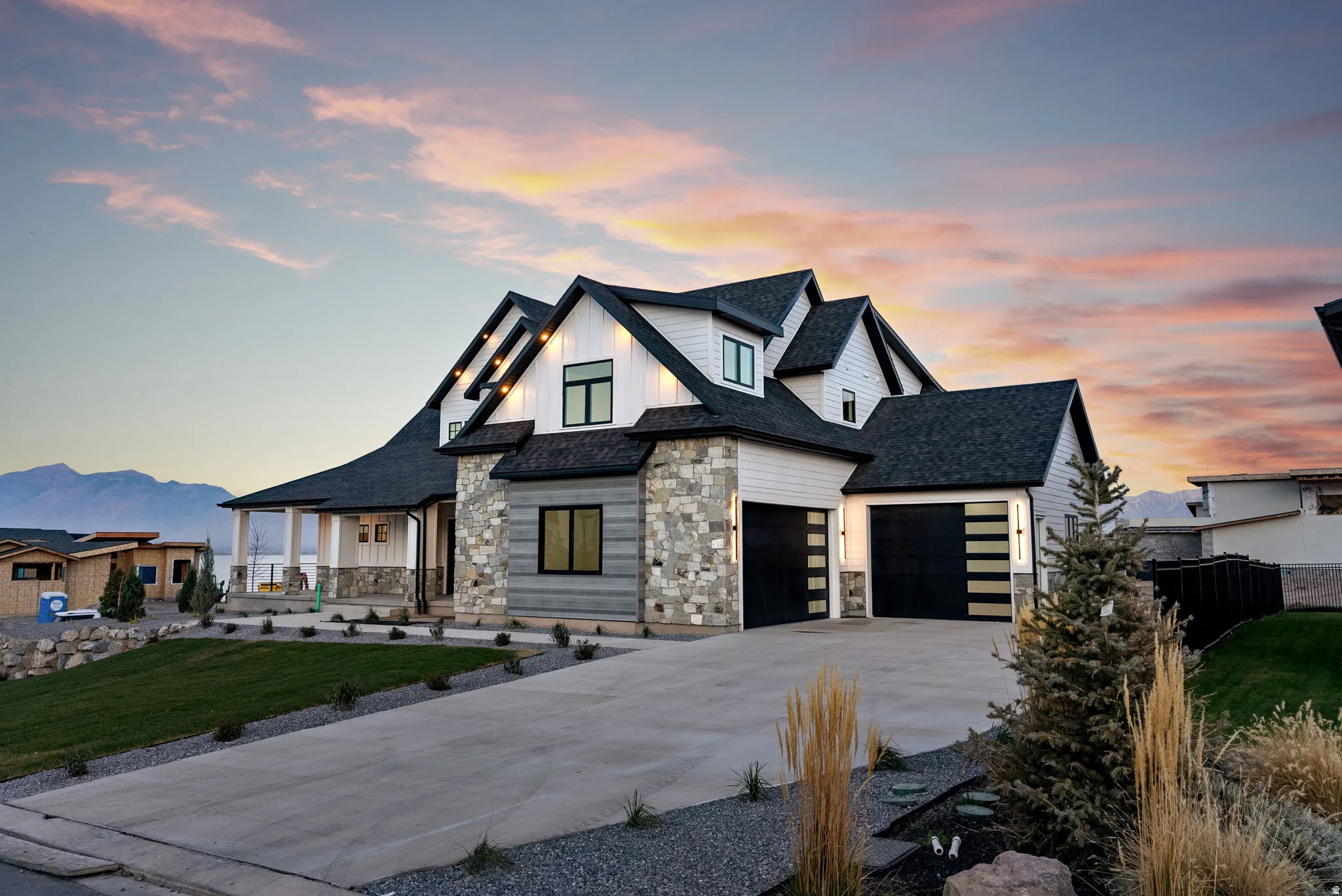 Modern-style residence featuring stone and siding exterior, multi-pitched roofline, two-car garage, and concrete driveway