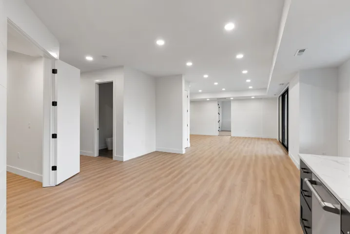 Spacious open-concept area featuring wood-finish flooring, recessed lighting, and white walls