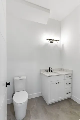 White vanity with black hardware, stone-finish countertop, and black faucet