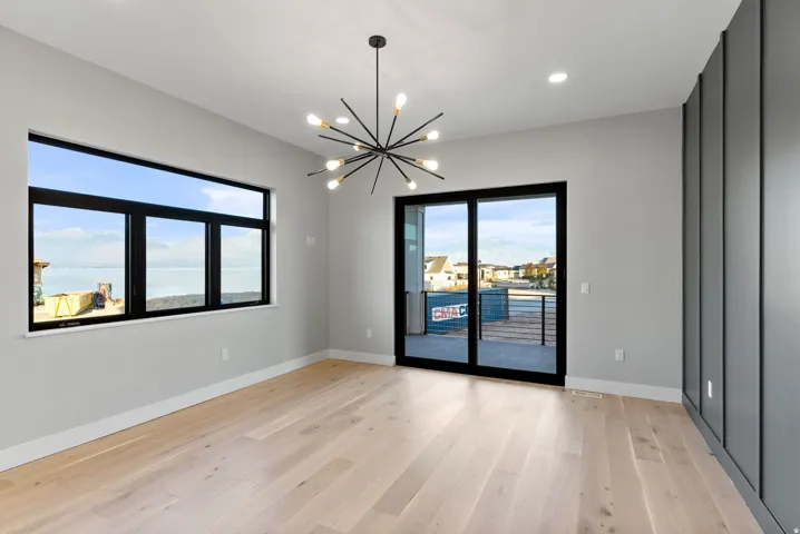 Light wood-finish flooring, a contemporary sputnik chandelier, recessed lighting, and a large window with water scenery