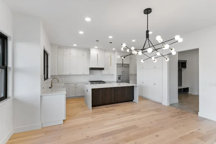 Light wood-finish flooring with a kitchen island featuring a dark wood base and white countertop