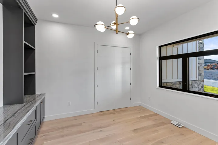 Recessed ceiling lighting, wood-finish flooring, built-in shelving, built-in cabinetry with stone countertop, and a modern chandelier