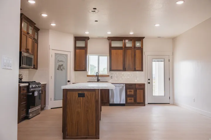 Kitchen featuring wood cabinetry, stainless steel appliances, a center island with a stone countertop, a tile backsplash, and recessed lighting