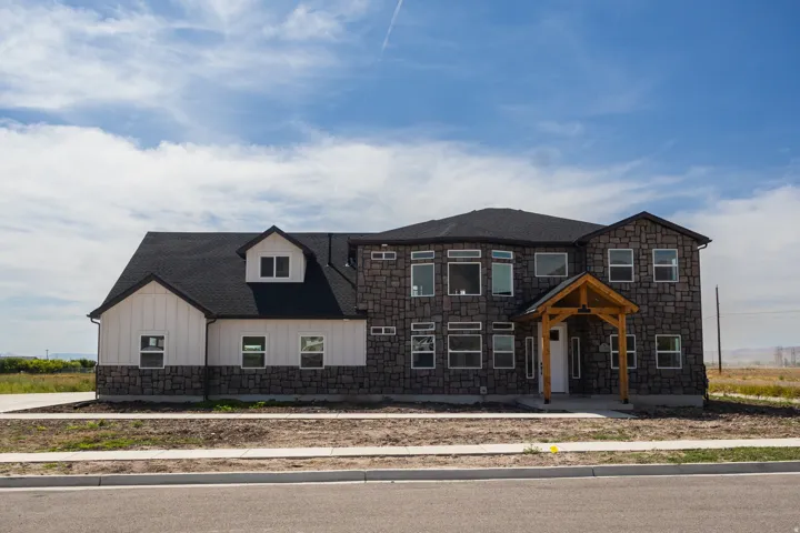 Stone and vertical siding exterior with a wood-framed porch entry
