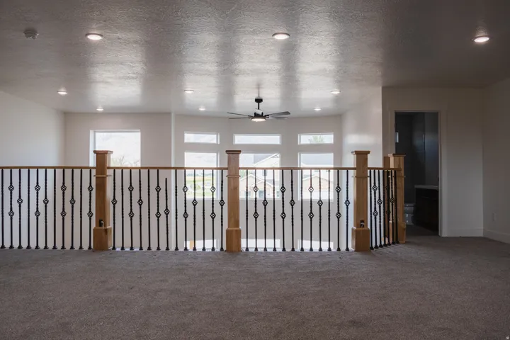 Open loft area with carpet flooring, recessed lighting, and a ceiling fan