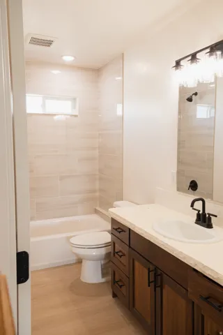 Wood-finish flooring with a white vanity featuring dark wood cabinetry and a light-toned countertop