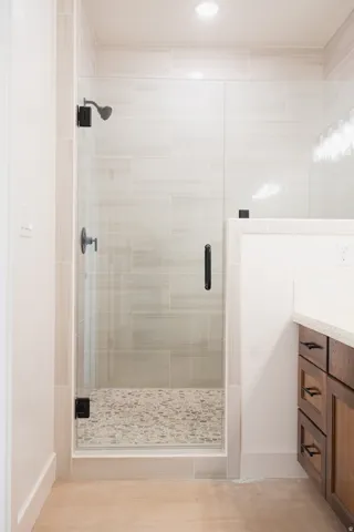 Glass-enclosed shower with pebble-tile flooring and matte black fixtures