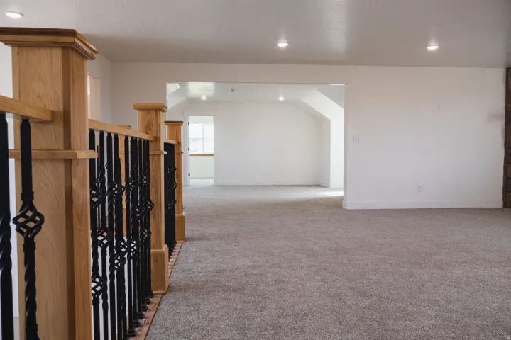 Carpeted flooring, recessed lighting, and a wood and wrought iron staircase railing