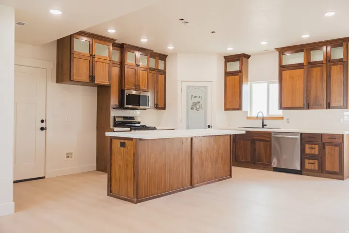 Kitchen featuring wood-finish cabinetry, stainless steel appliances, a center island with countertop, recessed lighting, and wood-finish flooring