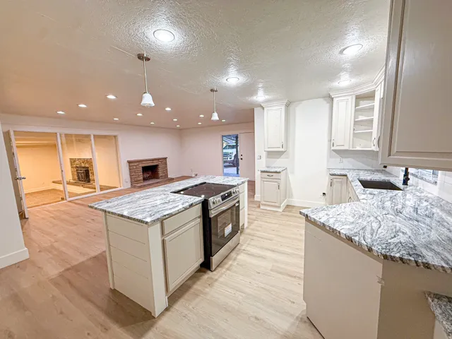 Kitchen featuring light wood-finish flooring, white cabinetry, dark countertops, and a stainless steel range