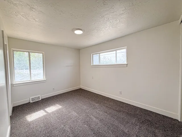 Textured ceiling, recessed lighting, and gray carpet flooring
