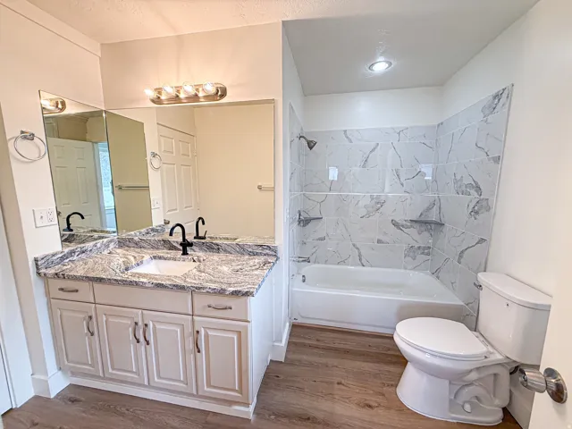 Vanity with a granite countertop, white cabinetry, and matte black fixtures