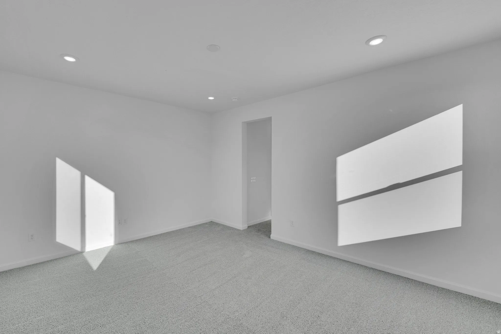 Recessed lighting with a light gray carpet and white walls