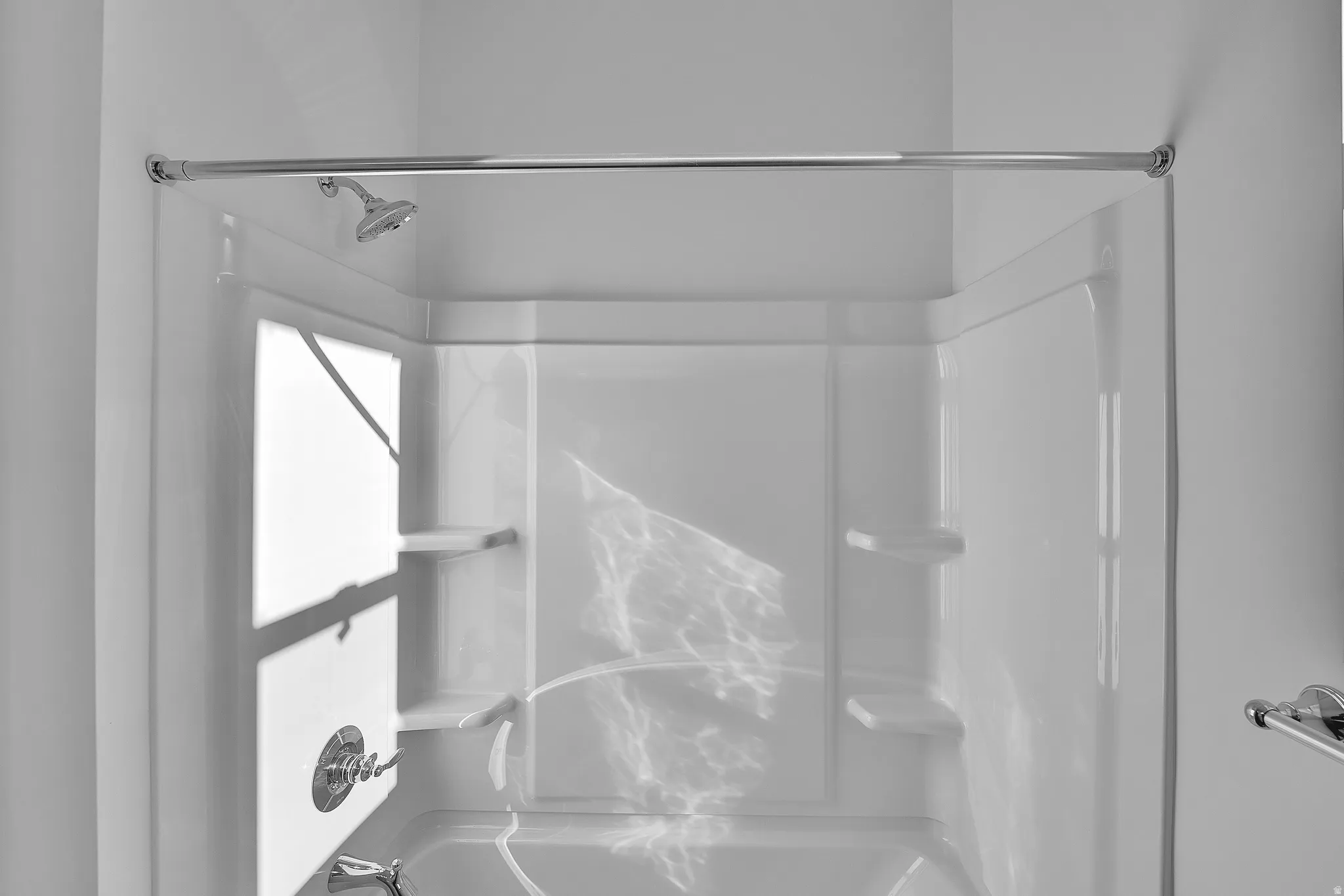 White fiberglass tub and shower combination with chrome fixtures and built-in shelving