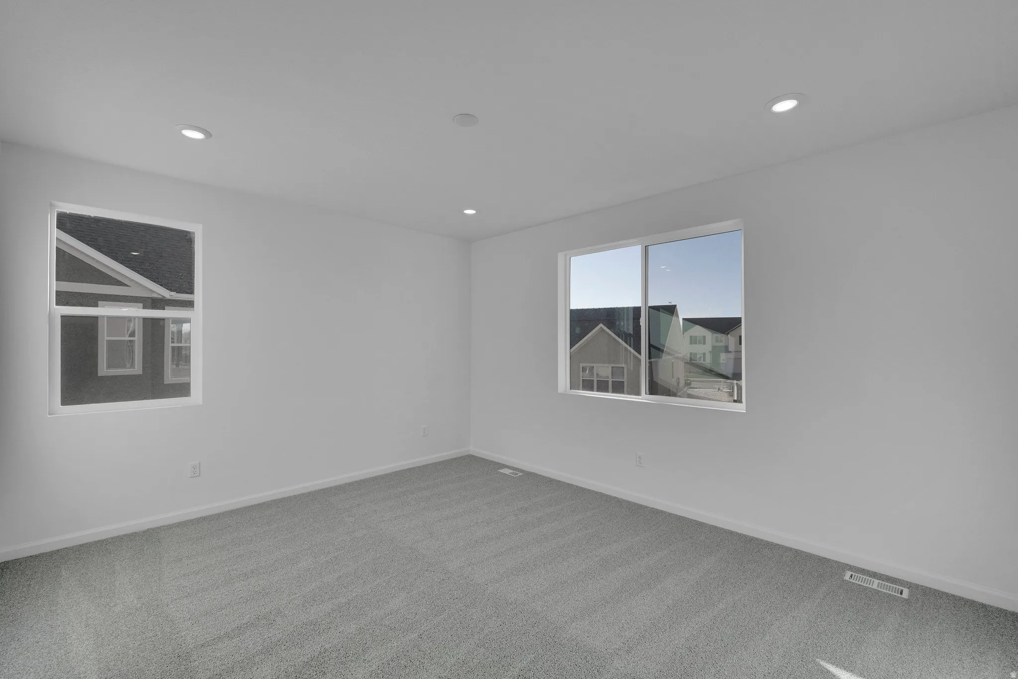 Recessed lighting, light gray carpeting, and multiple windows with white trim