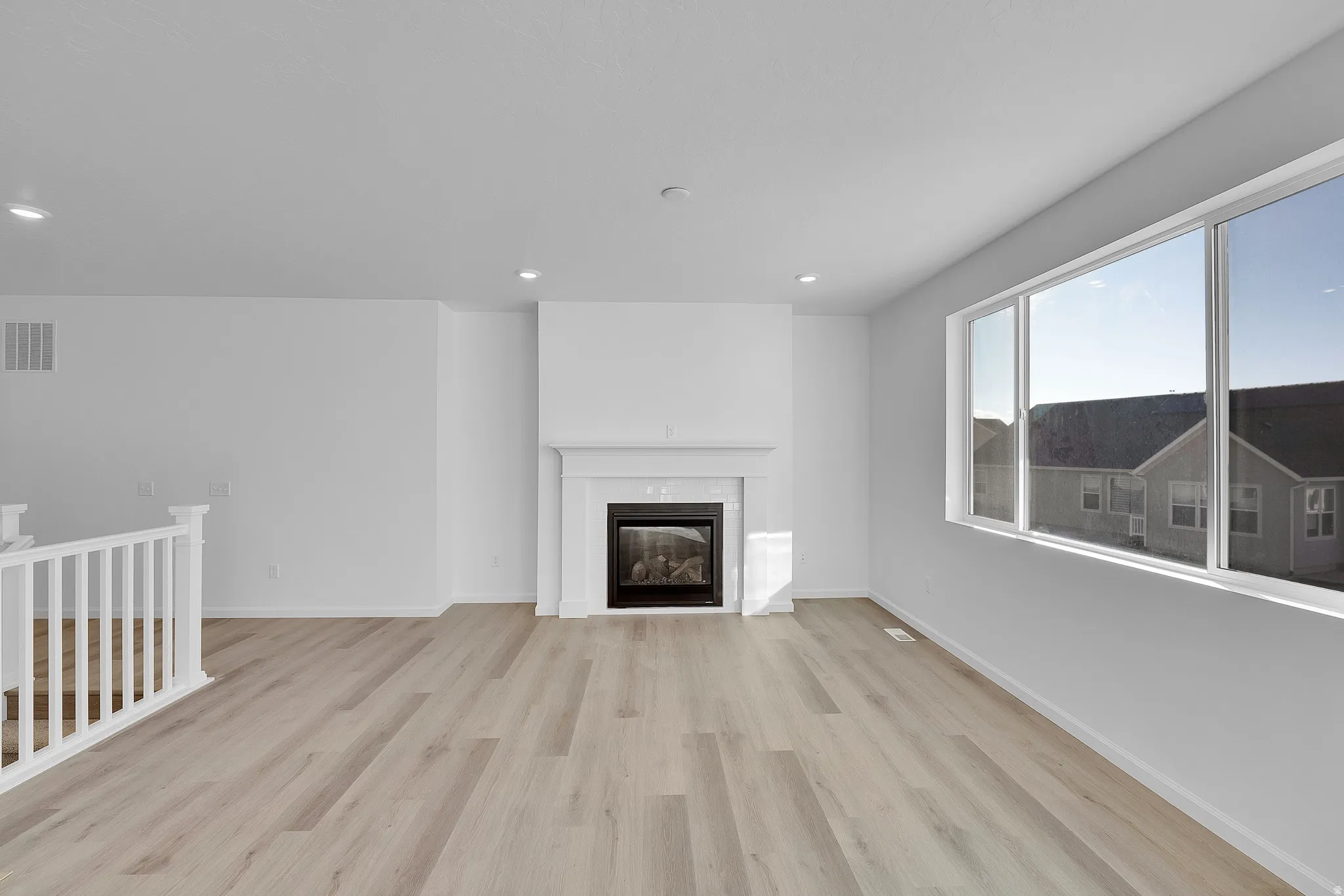 Expansive room featuring wood-finish flooring, a contemporary fireplace with a mantel, and recessed lighting