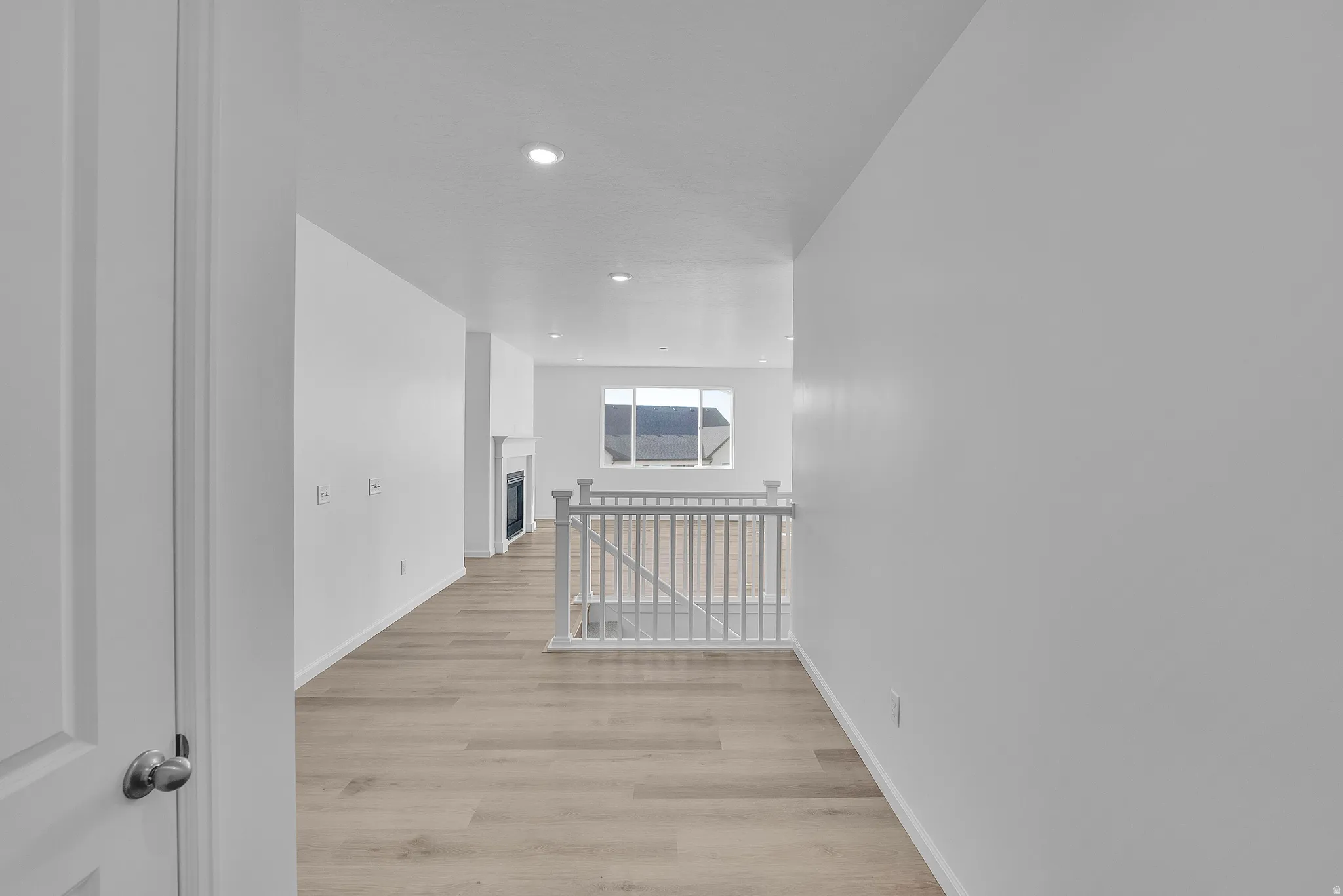 Neutral wall colors, wood-finish flooring, recessed lighting, and a fireplace with a white mantle