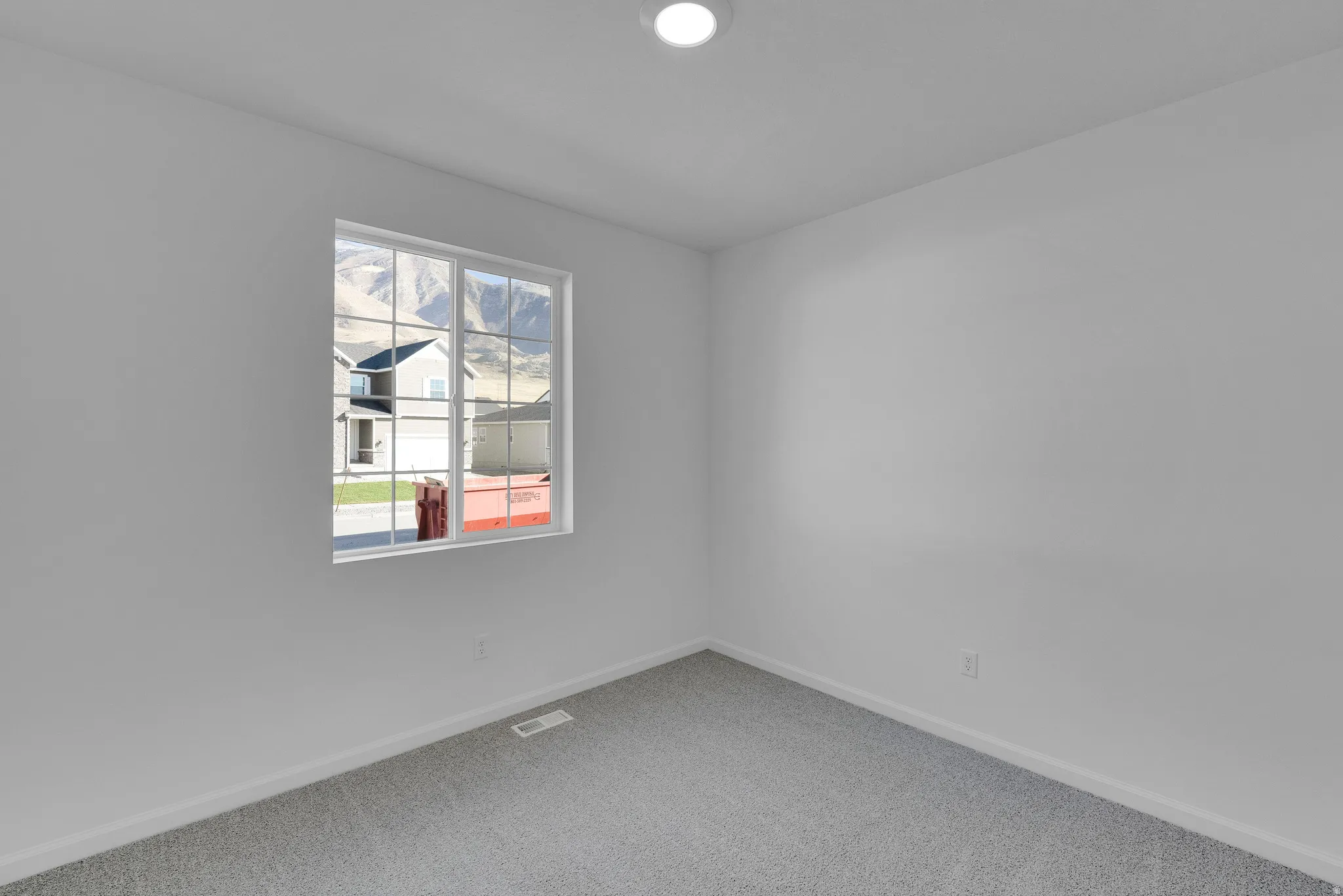 White walls with gray carpeting, recessed ceiling lighting, and a multi-pane window with mountain scenery