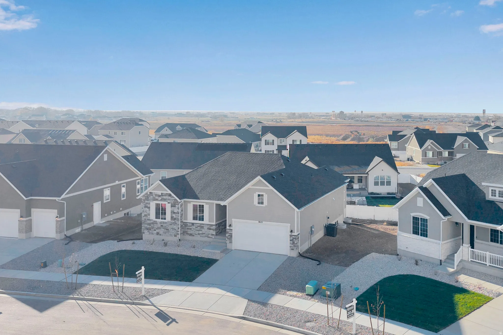 Single-story residence featuring a light gray exterior, dark shingle roof, and a stone facade accent
