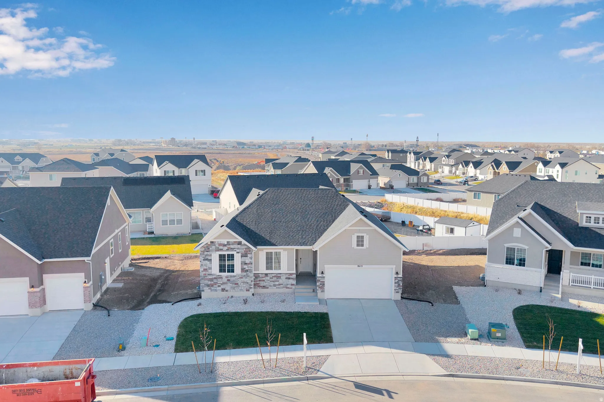 Single-story residence featuring a two-car garage, stone and siding exterior, and a paved driveway