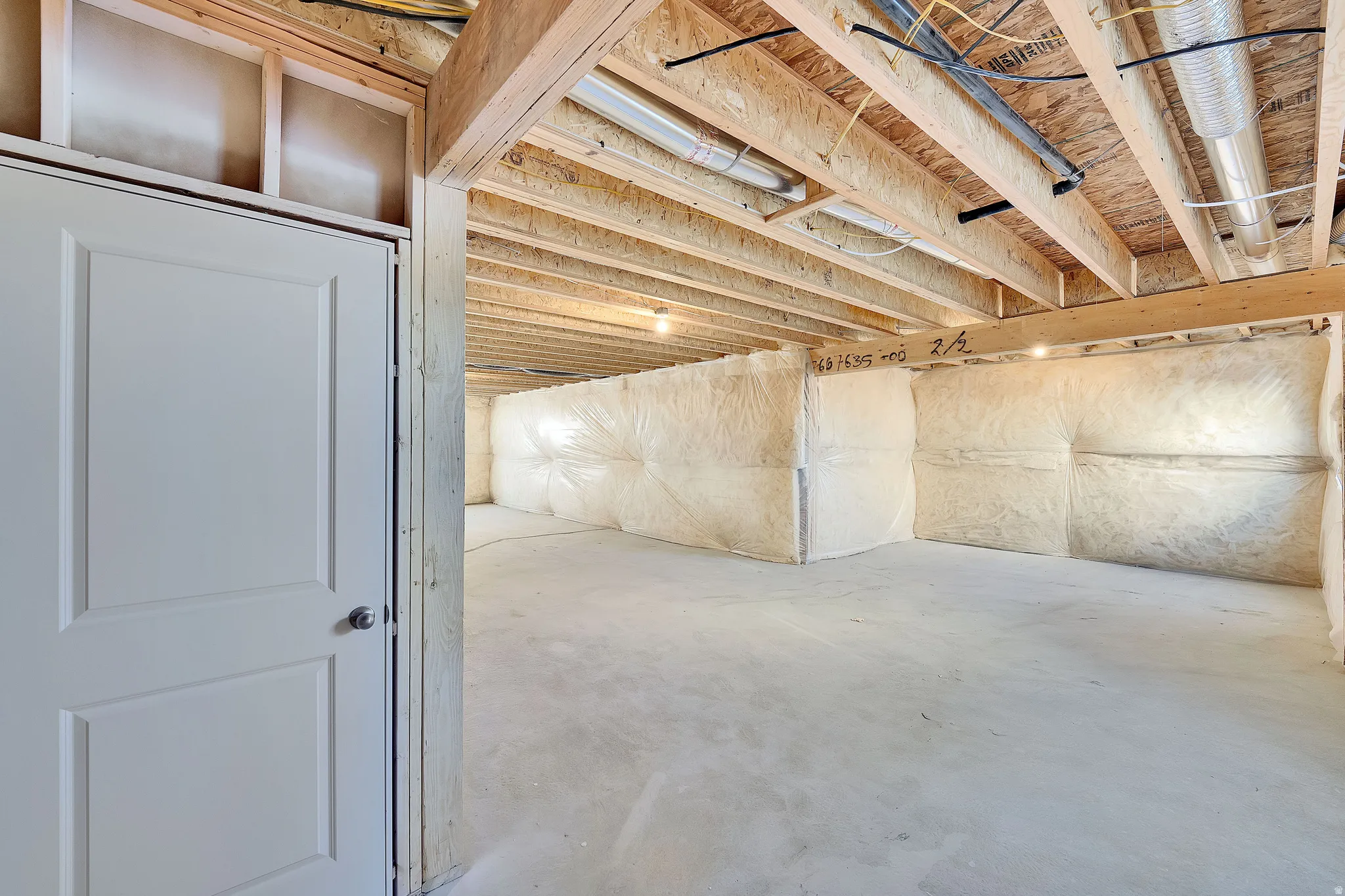 Unfinished lower level with exposed ceiling joists, concrete flooring, and insulated walls