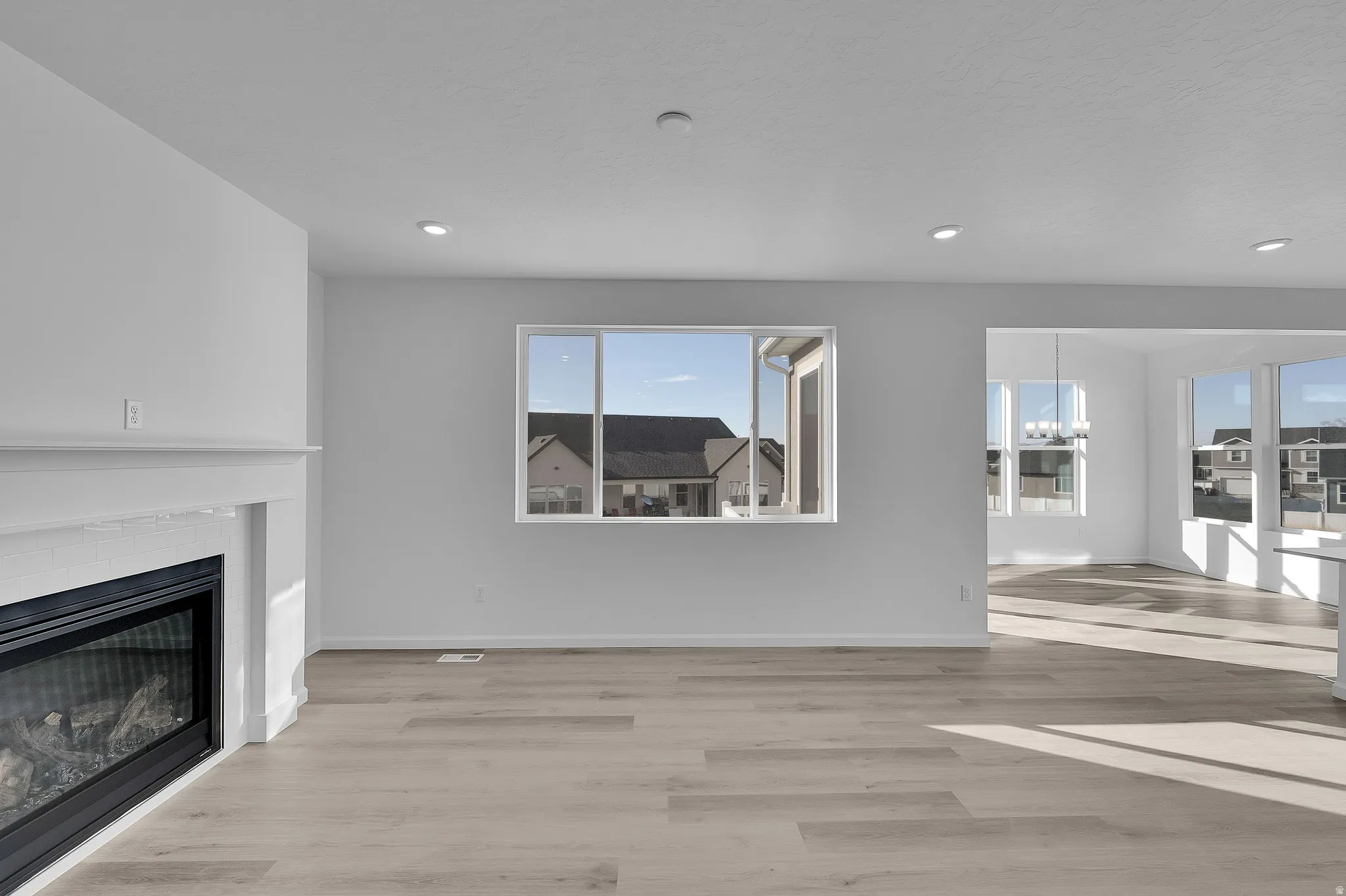 Built-in fireplace with a white mantel, recessed lighting, wood-finish flooring, and multiple windows