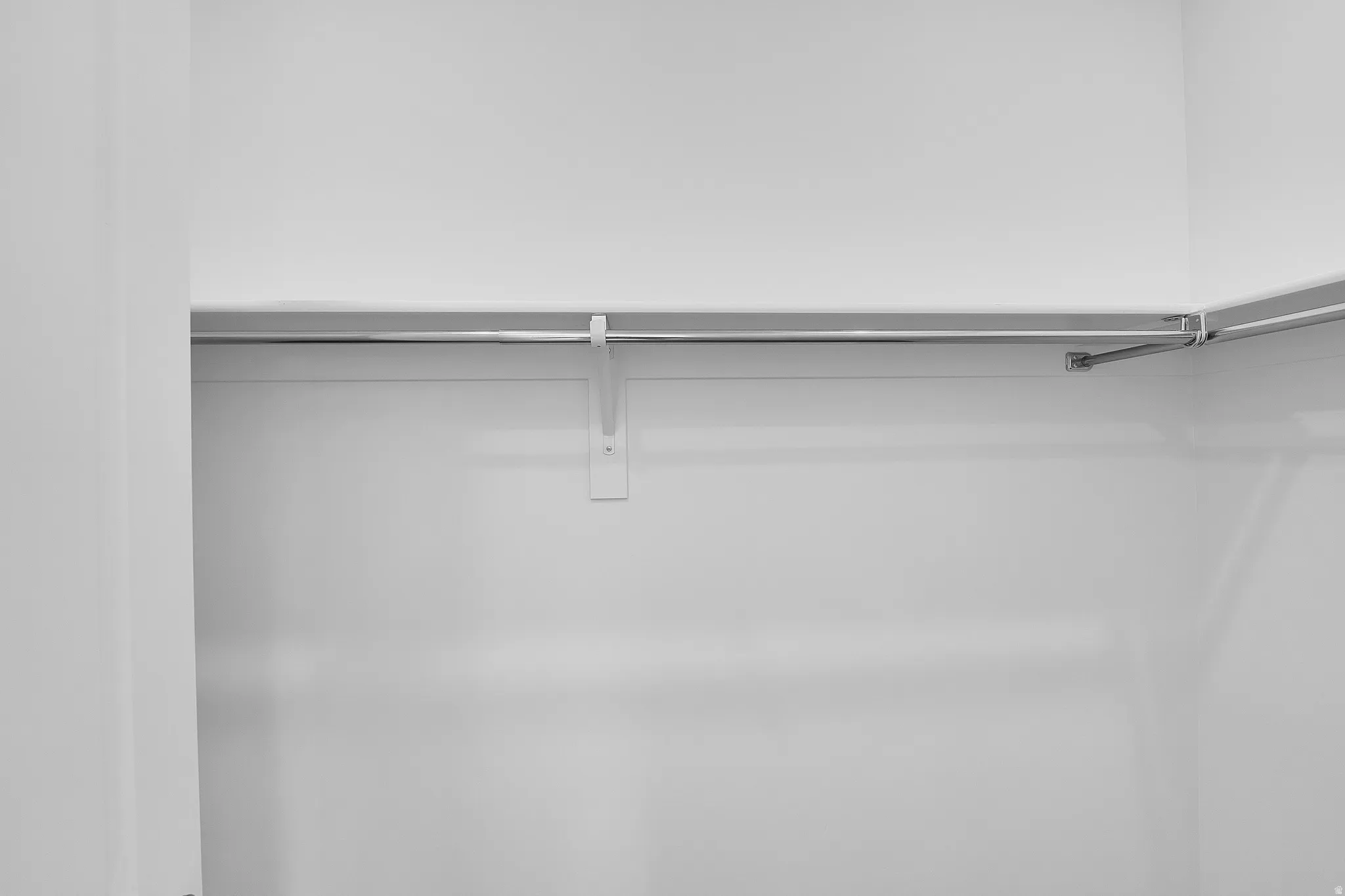White-painted closet interior with an integrated shelf and clothing rod