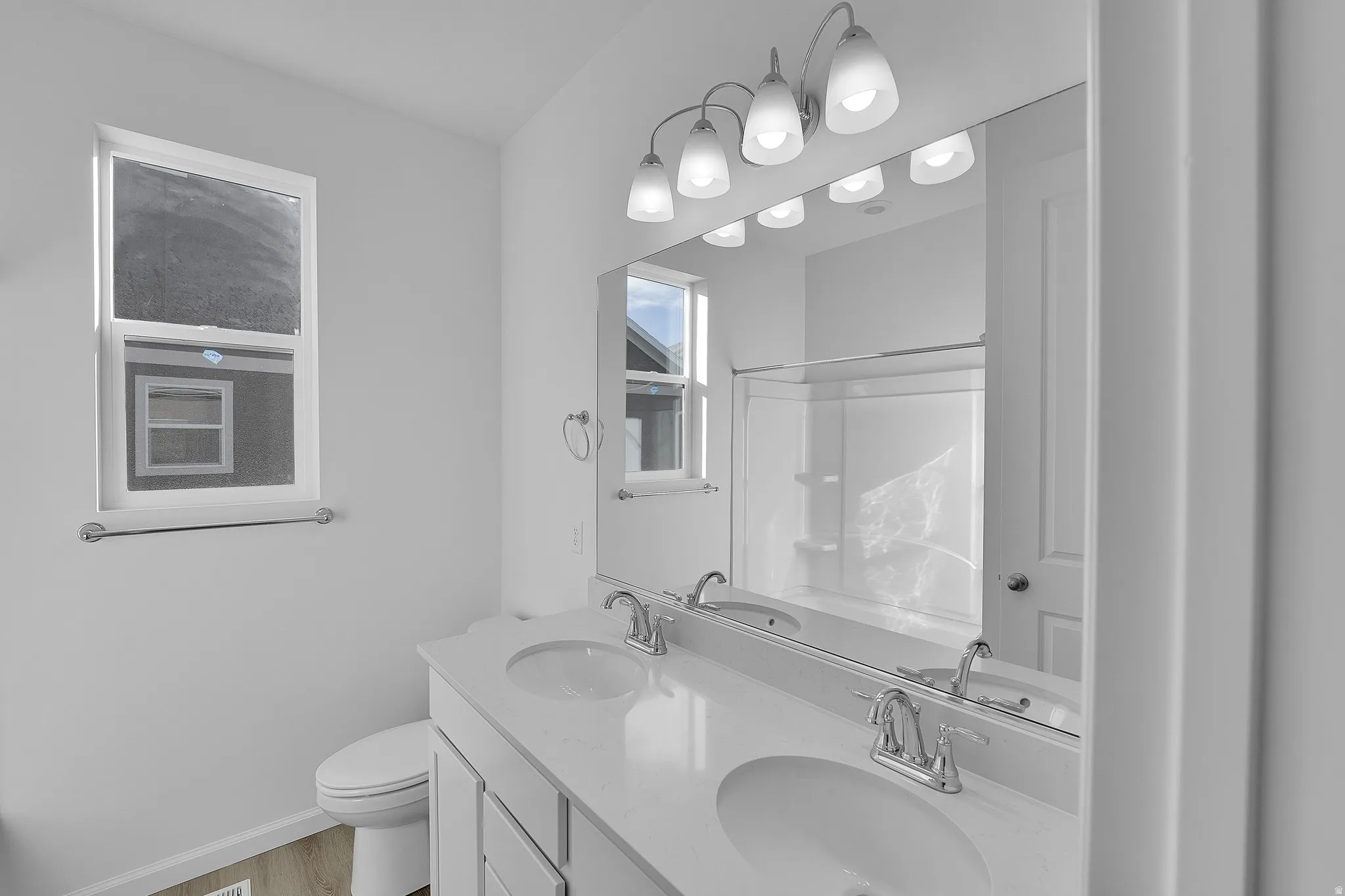 Double vanity with integrated sinks, white cabinetry, chrome fixtures, and a large wall-mounted mirror
