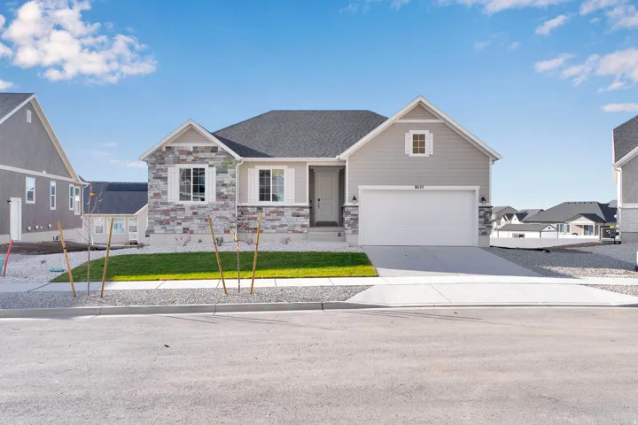 Exterior featuring mixed material facade, attached garage, concrete driveway, and front lawn