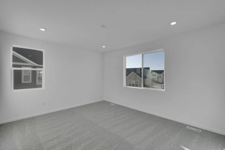Recessed lighting, light gray carpeting, and multiple windows with white trim