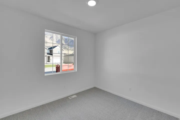 White walls with gray carpeting, recessed ceiling lighting, and a multi-pane window with mountain scenery