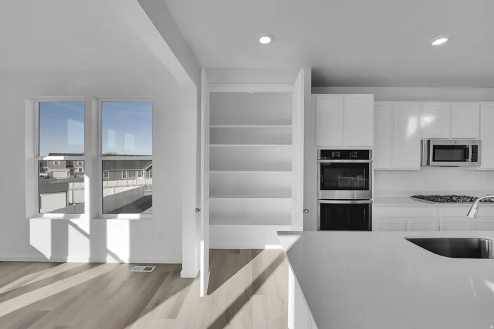 Open-concept kitchen with white cabinetry, stainless steel double ovens, and a built-in microwave