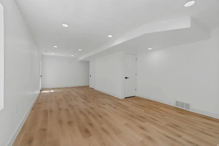 Spacious room featuring wood-finish flooring, recessed lighting, and white walls