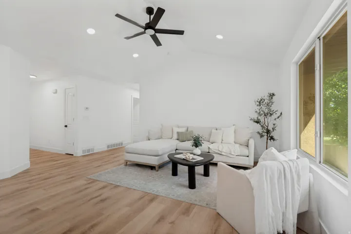 Vaulted ceiling with a ceiling fan, recessed lighting, wood-finish flooring, and expansive windows