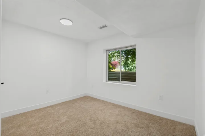 Neutral wall finishes, recessed lighting, carpet flooring, window with exterior foliage