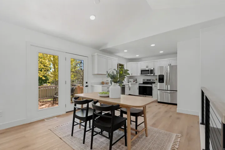 Open-concept kitchen with light wood-finish flooring, white cabinetry, stainless steel appliances, and recessed lighting