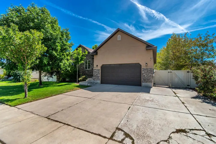 Two-story exterior with stucco and stone accents, an attached two-car garage, and a gated side entrance