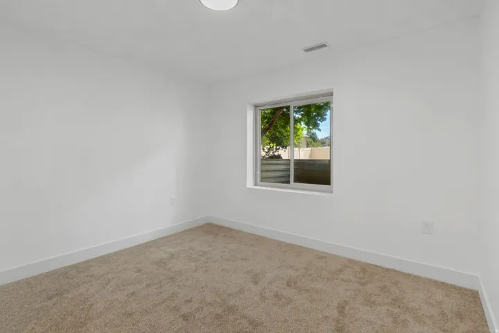 Recessed lighting, neutral tone carpeting, white painted walls, and a sliding window