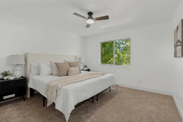 Neutral color palette with expansive walls, recessed window, and a ceiling fan with integrated lighting
