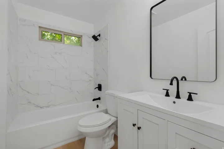 White vanity with matte black hardware, integrated sink, and modern black-framed mirror