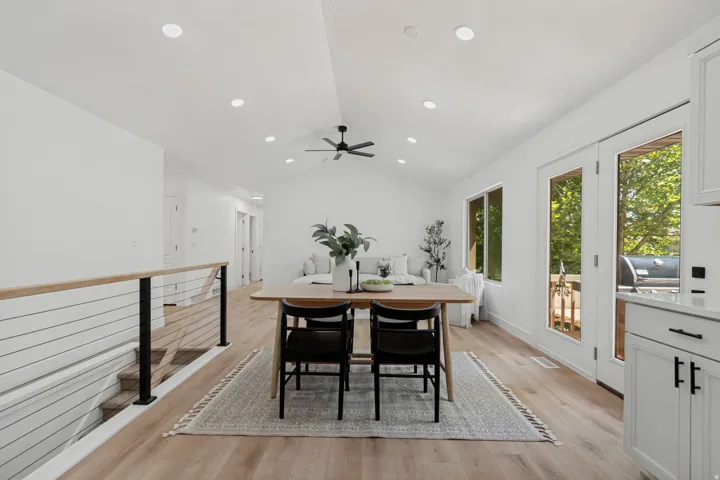 Vaulted ceiling with recessed lighting, wood-finish flooring, white walls, and a modern cable railing system