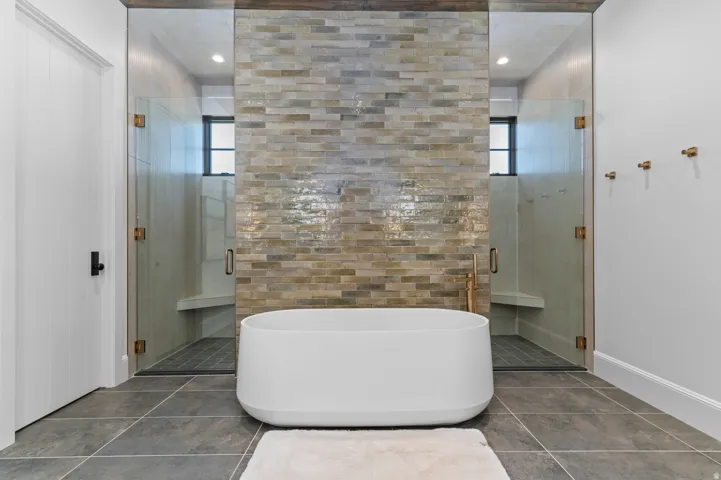 Freestanding soaking tub with a stacked stone accent wall