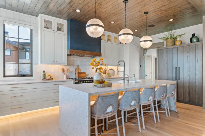 Wood-finish plank ceiling and flooring, white shaker cabinetry with undermount lighting, and a kitchen island with built-in seating