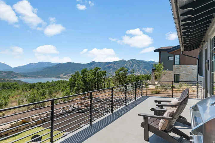 Spacious exterior deck with a black metal railing and mountain scenery