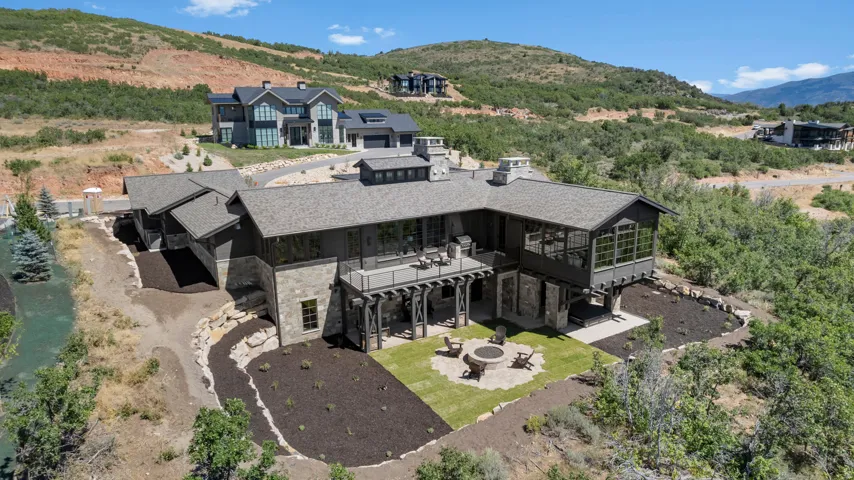 Modern mountain-style exterior with stone and wood siding, multiple rooflines, and an expansive upper-level deck
